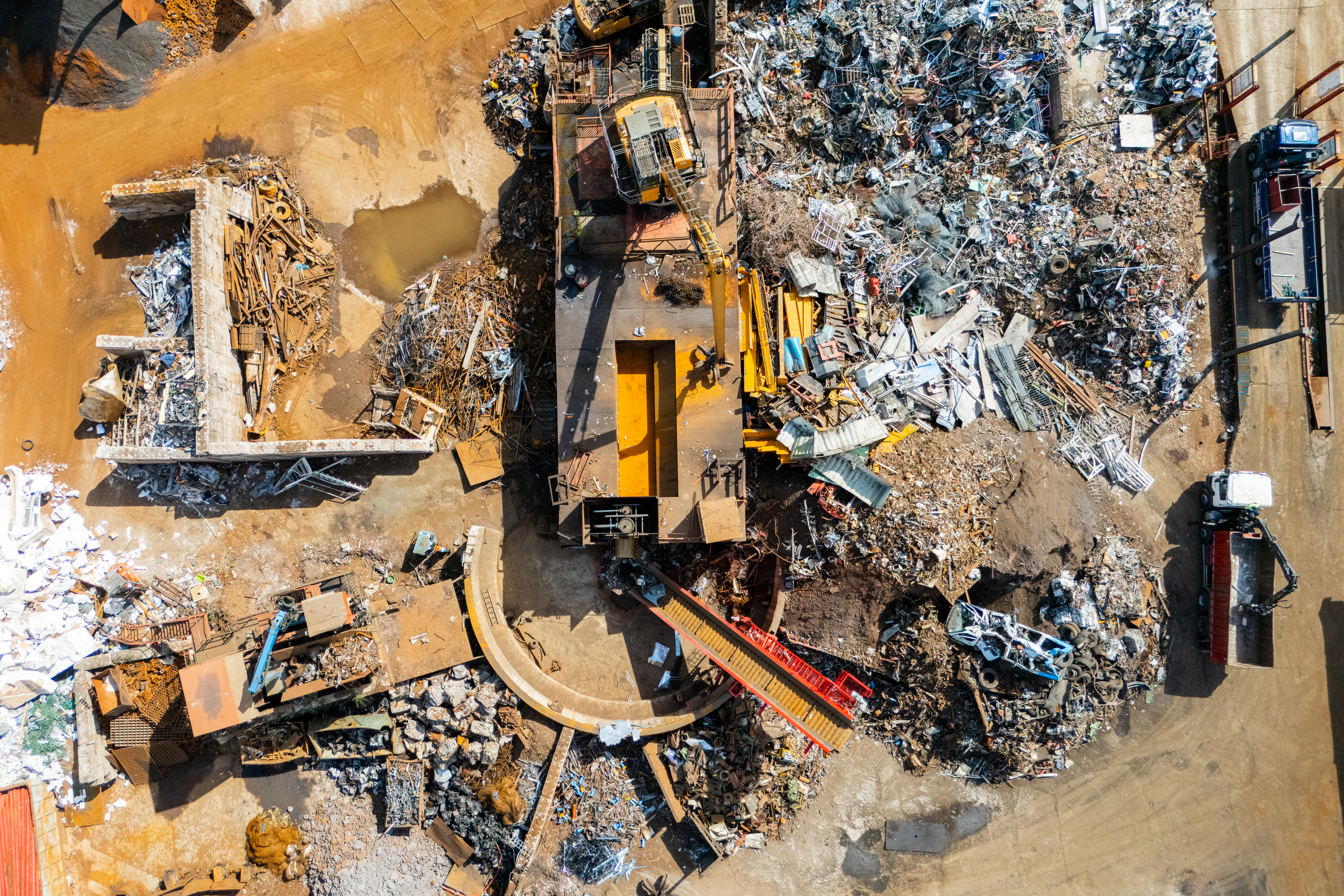 Aerial view of large metal scrap piles and heavy excavators at a industrial recycling facility